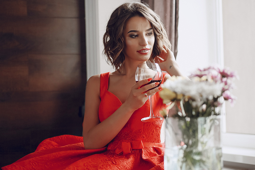 elegant and beautiful lady in red dress sitting in a restaurant with a glass of expensive wine